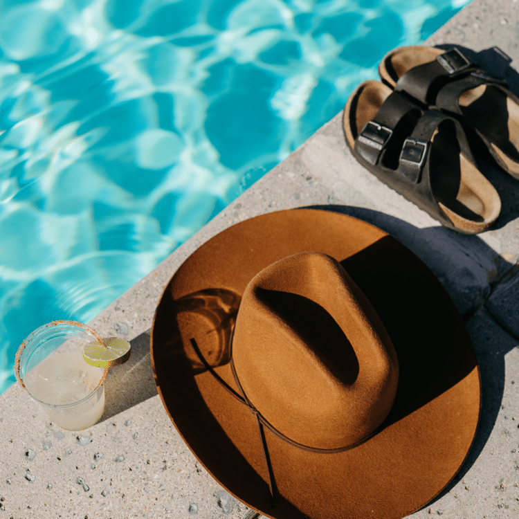 hat, cocktail and sandals by the pool